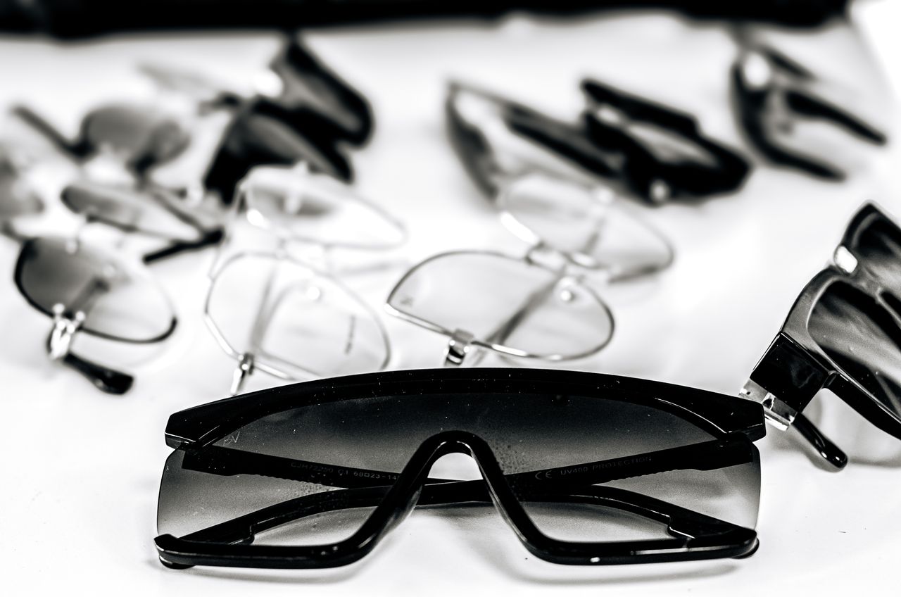 home-hero Close-up of various stylish sunglasses and eyeglasses on a white surface, showcasing modern eyewear design.