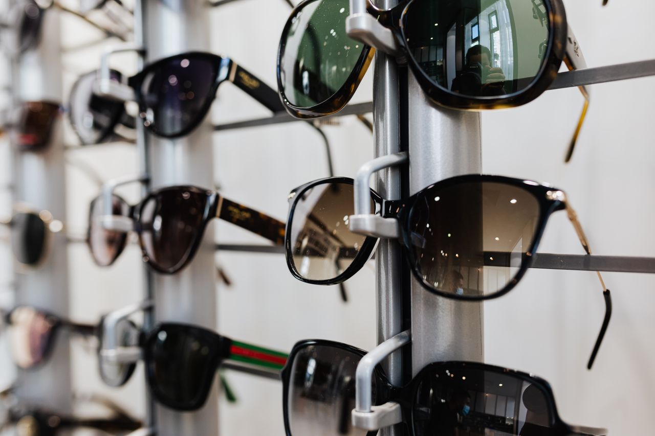 about-us Close-up view of stylish sunglasses displayed on a rack in a retail store.